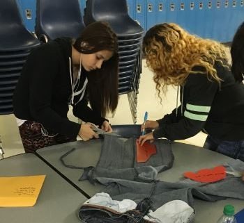 AVID sophomores Stephanie Leyva and Ana Rivera begin the process of cutting out denim to create shoes for Ugandans.  