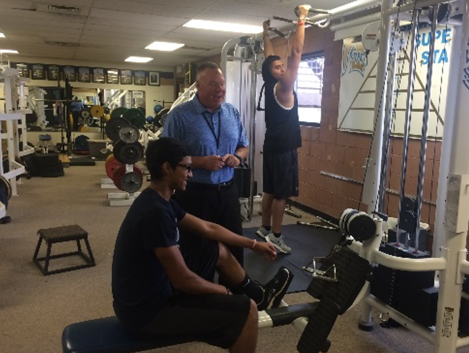 Mr. Ken Denning talks with Luis Deleon in the weight room on Wednesday.  Denning is enjoying his first few weeks as athletic director at West.