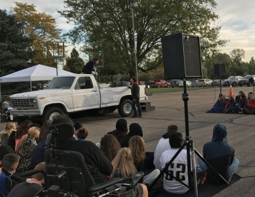 Greeley West students sit outside and watch the Denver Performing Arts actors perform Shakespeare in the parking lot.
