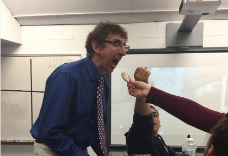 Mr. Curt Miller is fed a cookie that he brought to his class to celebrate Pi Day on Tuesday.