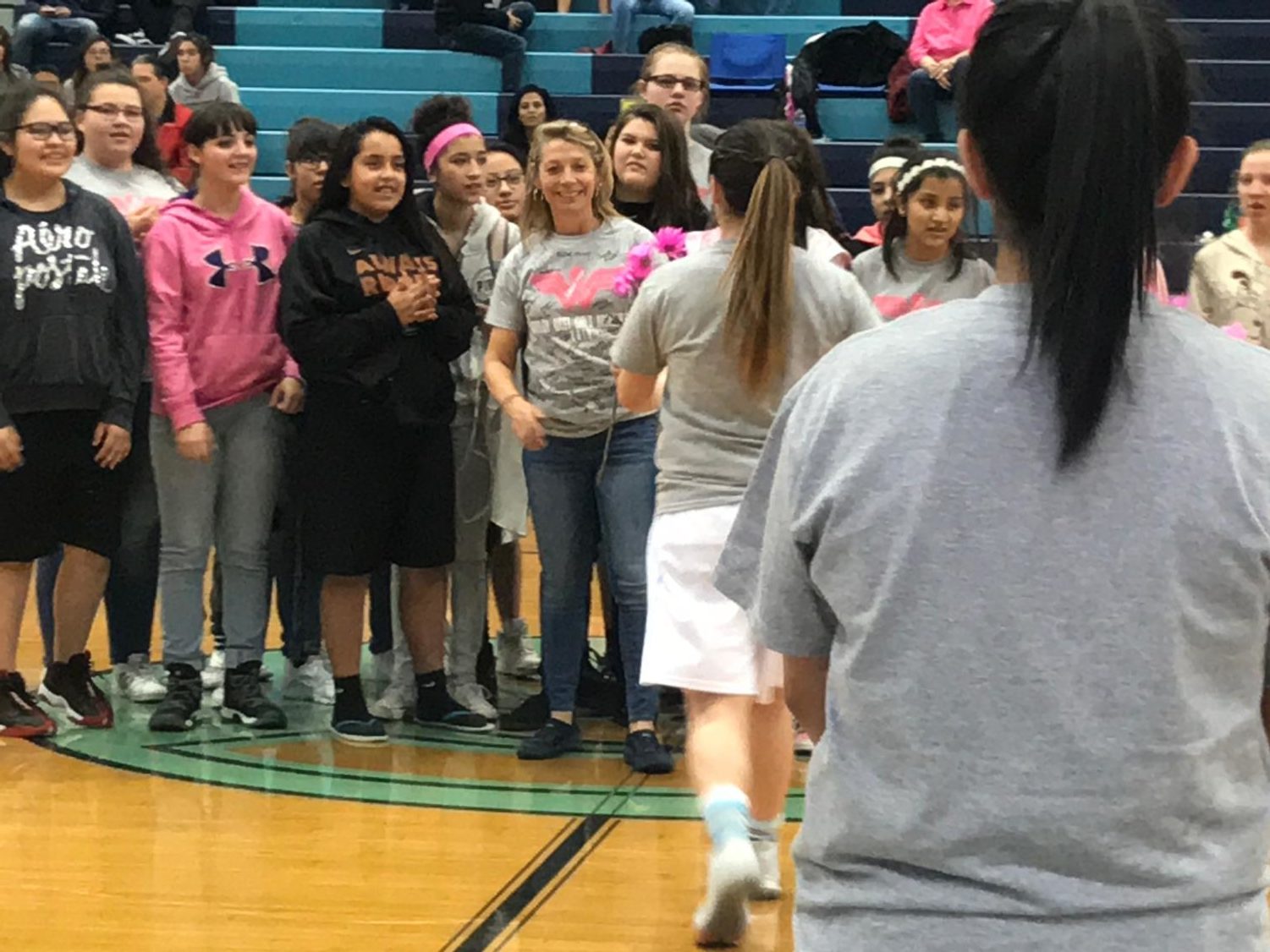 Brentwood Middle School teacher, Laurie Ford, is recognized with pink flowers by the girls basketball team before Tuesday nights game at Greeley West.