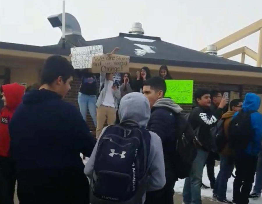 Students hold signs while others look at their cell phones during a student protest at Greeley West High School on Friday.