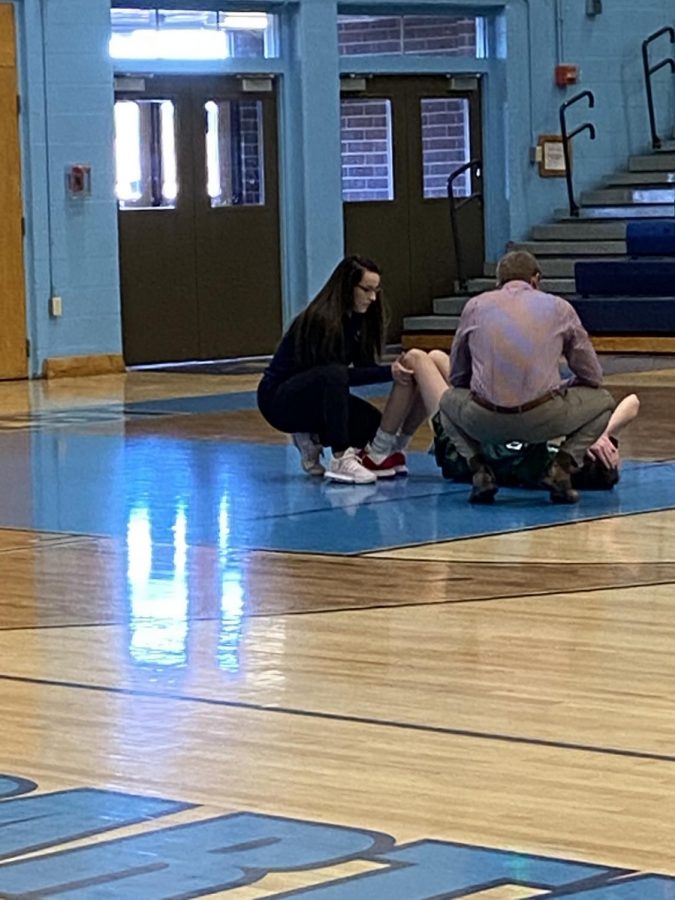 Greeley West trainer Ali Curtis works with a Mountain Vista student who appeared to hyper-extend his knee during the JV basketball on Saturday.