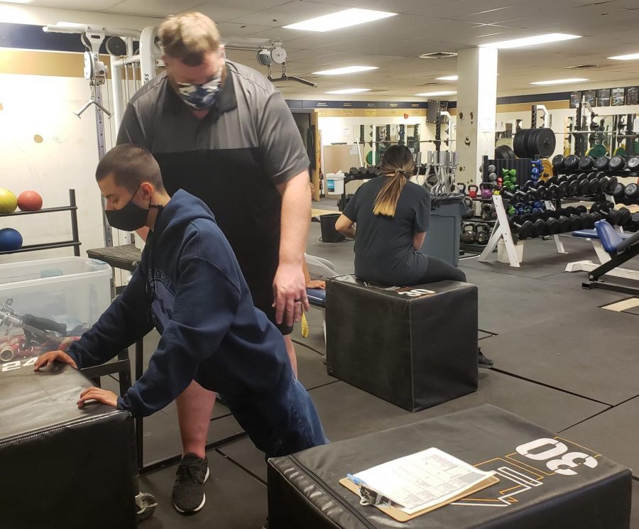 Greeley West PE teacher Mr. Ryan Walstrom works with senior Jake Horner on Monday.  In addition to teaching his classes, Walstrom is working as an administrative intern as he works toward his administration license. 