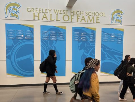 Greeley West students walk by the Hall of Fame plaques outside of the gym.