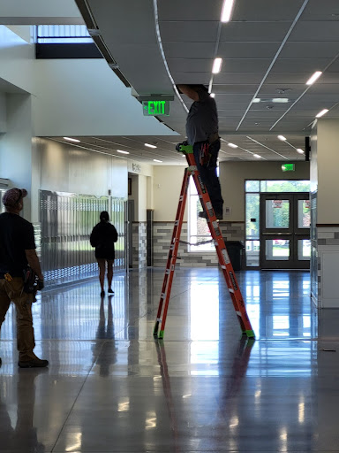 Workers check light fixtures in the hallways this week at Greeley West High School. 