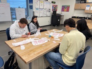 Greeley West AVID sophomores Xavier Blackwell and Aileen Mendiola Morales craft a mat for homeless people to sleep on during AVID class on Monday.
