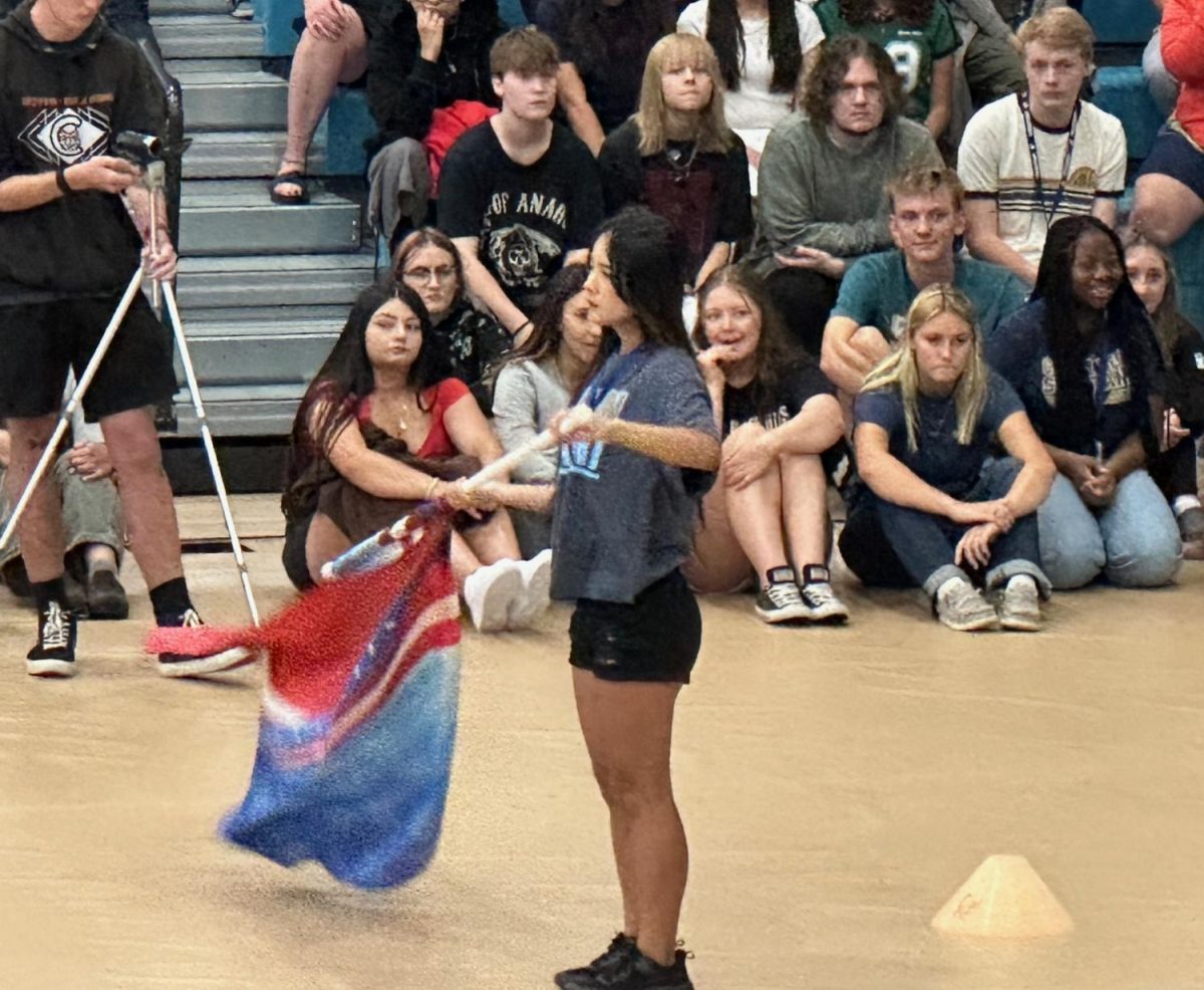 Sophomore band member Serena Paw twirls her flag in unison with the band's music during Tuesday's opening day assembly.  