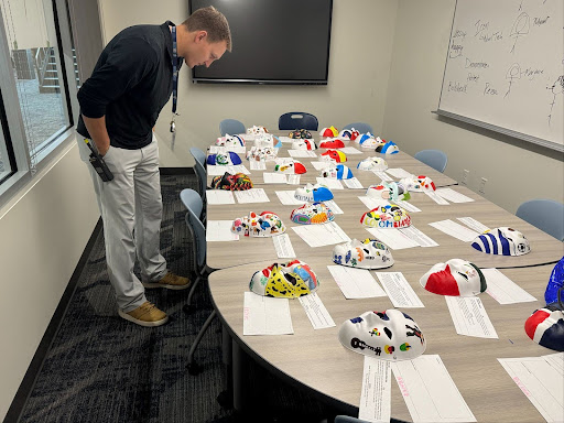 Assistant Principal Kyle Appelhans explores the AP Spanish mask project in the English hallway.