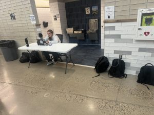 Campus monitor Rose Francis monitors video while sitting in front of the restrooms during B lunch on Thursdsay.  Backpacks wait for their student to claim them - another recent attempt at making West safer.